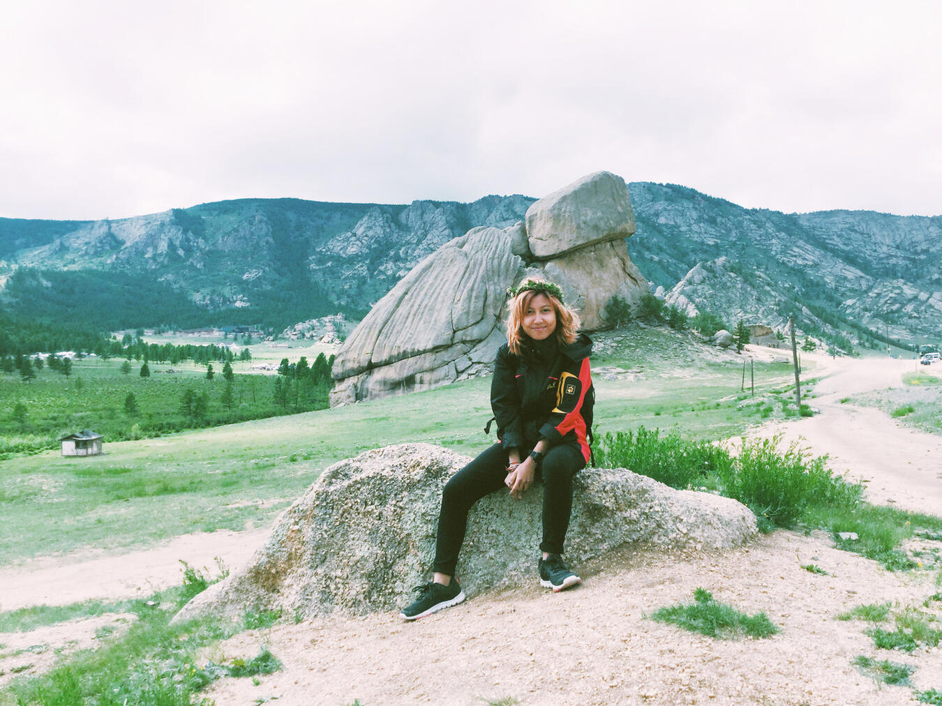 Ana Jonessy sitting on a boulder, in front of the Turtle Rock, known locally as "Mongol Urtyn Khad," in Gorkhi-Terelj National Park.